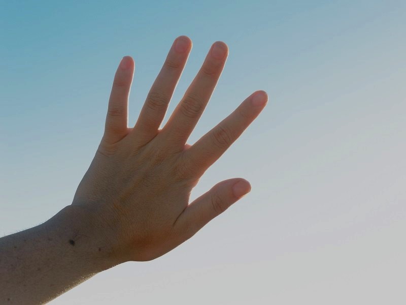 A girl screens her eyes from the sun light with a hand